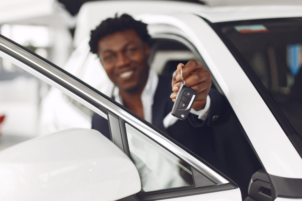 Smiling man holding car keys for white luxury car