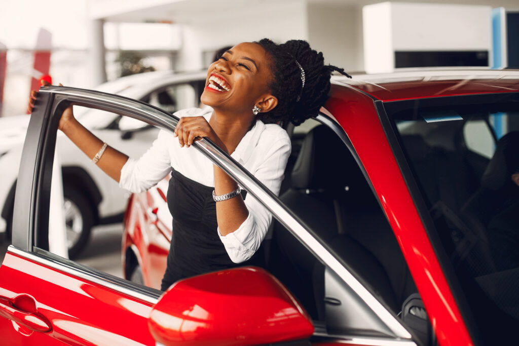 Laughing women opening red luxury car driver’s door