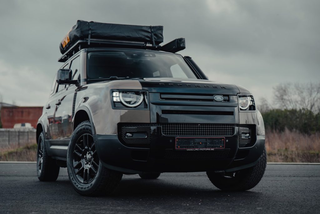 Landrover defender suv 4x4 vehicle with a roof rack packed for a trip