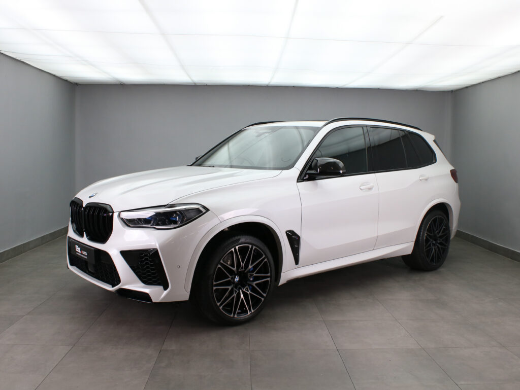White BMW SUV in a studio showroom, three-quarter front view with black alloy wheels and prominent kidney grilles