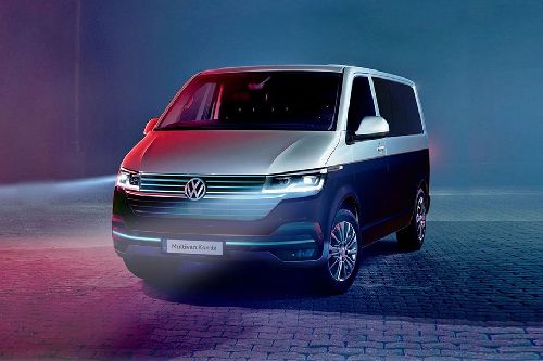 Volkswagen van shown from the front-left in a blue studio setting with red and blue lighting.