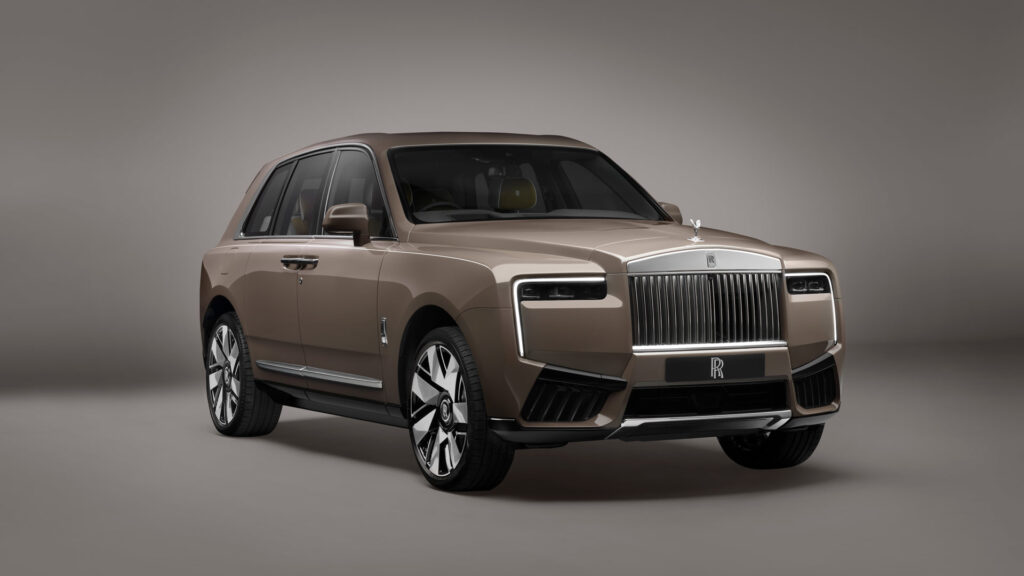 Beige Rolls-Royce SUV viewed from the front-right, featuring the signature vertical grille and Spirit of Ecstasy hood ornament.