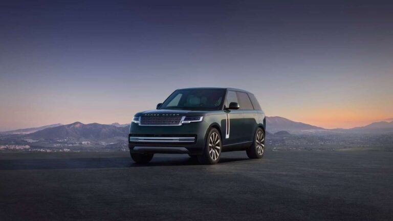 Range Rover SUV parked on a flat, open landscape with distant mountains at sunset.